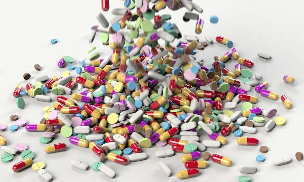 Pilules, gélules, cachets, comprimés colorés en tas.